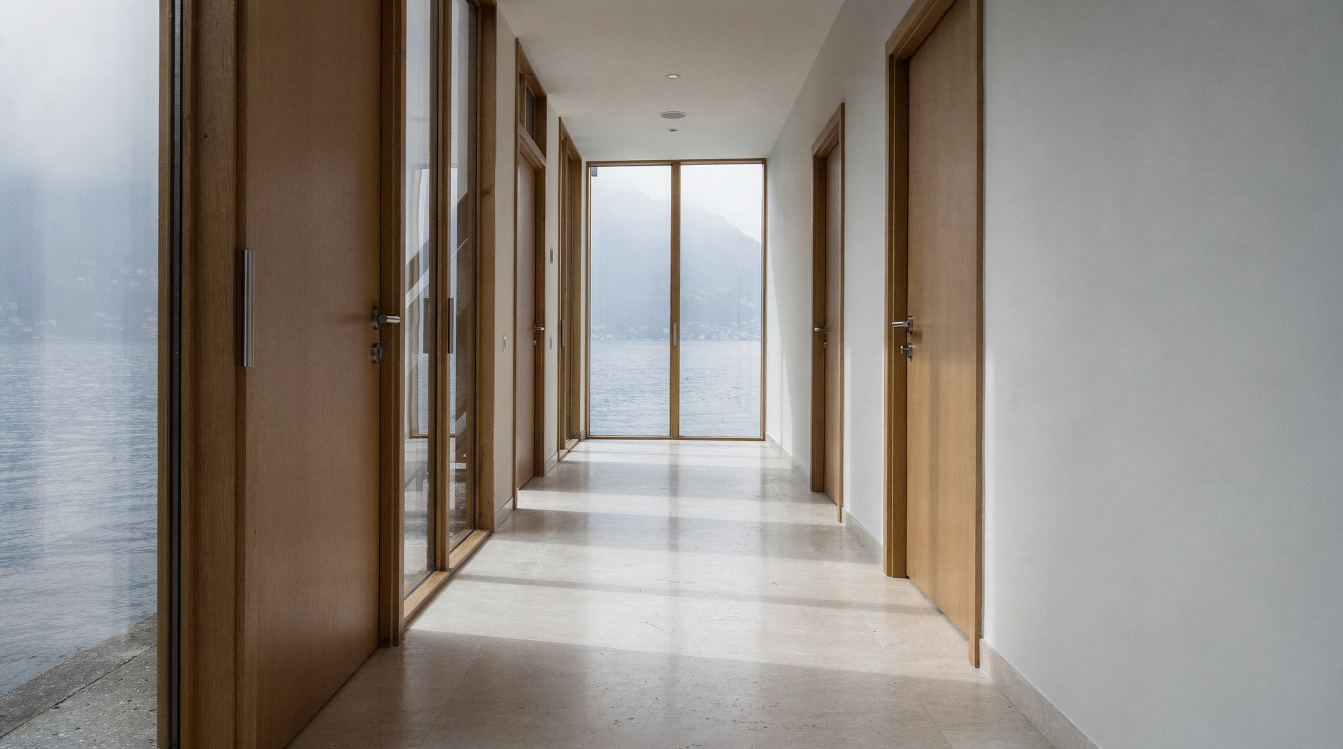 A quiet timber corridor leading to a window over water.