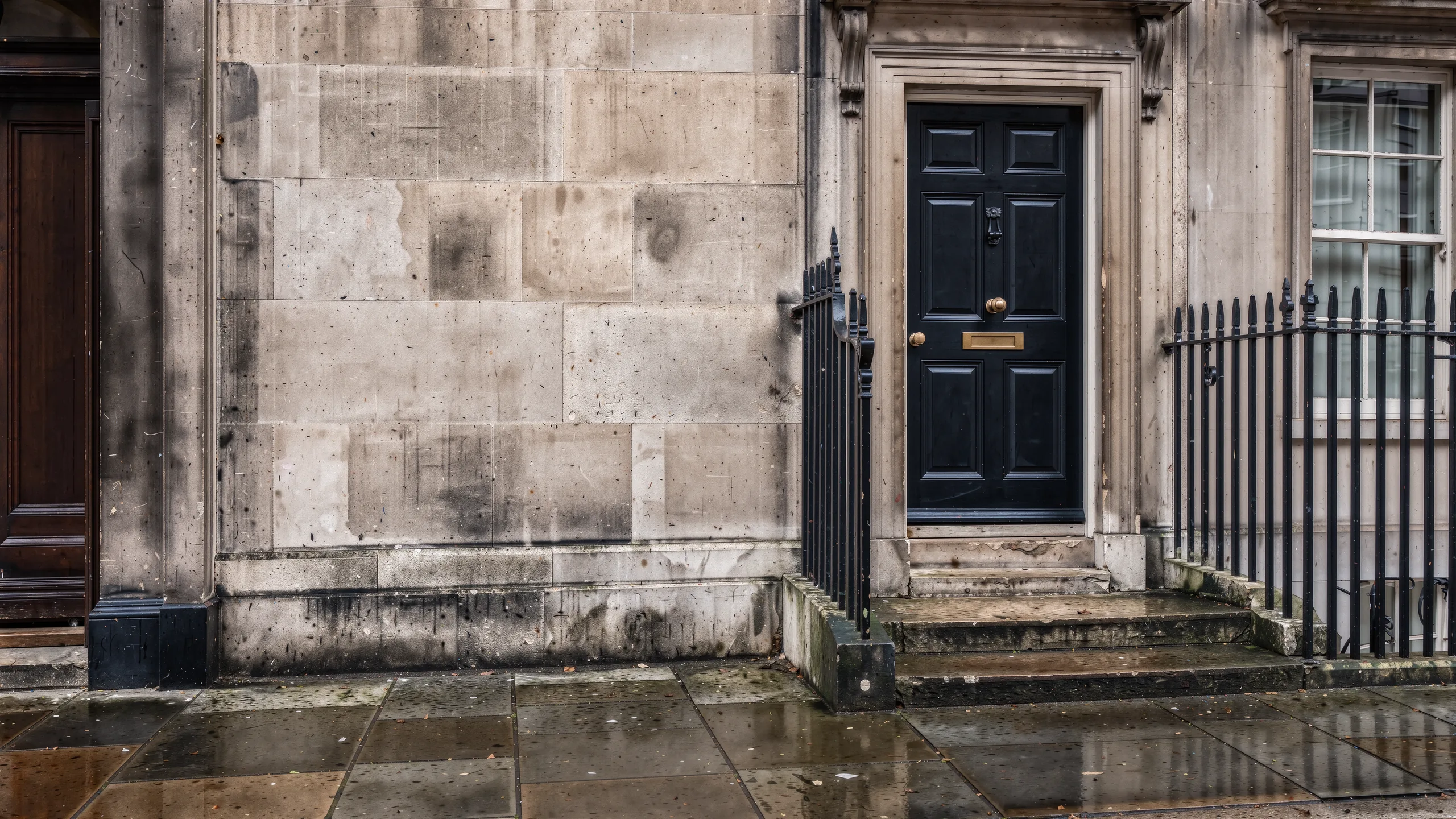 An illustrative Georgian financial house with Portland stone, a black timber door and wrought-iron railings.